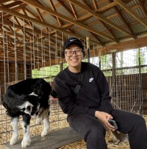 Florence Thwe sitting in a barn next to a dog